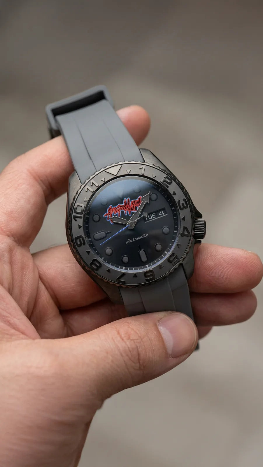 Client artwork on a dark dial with a grey rubber strap